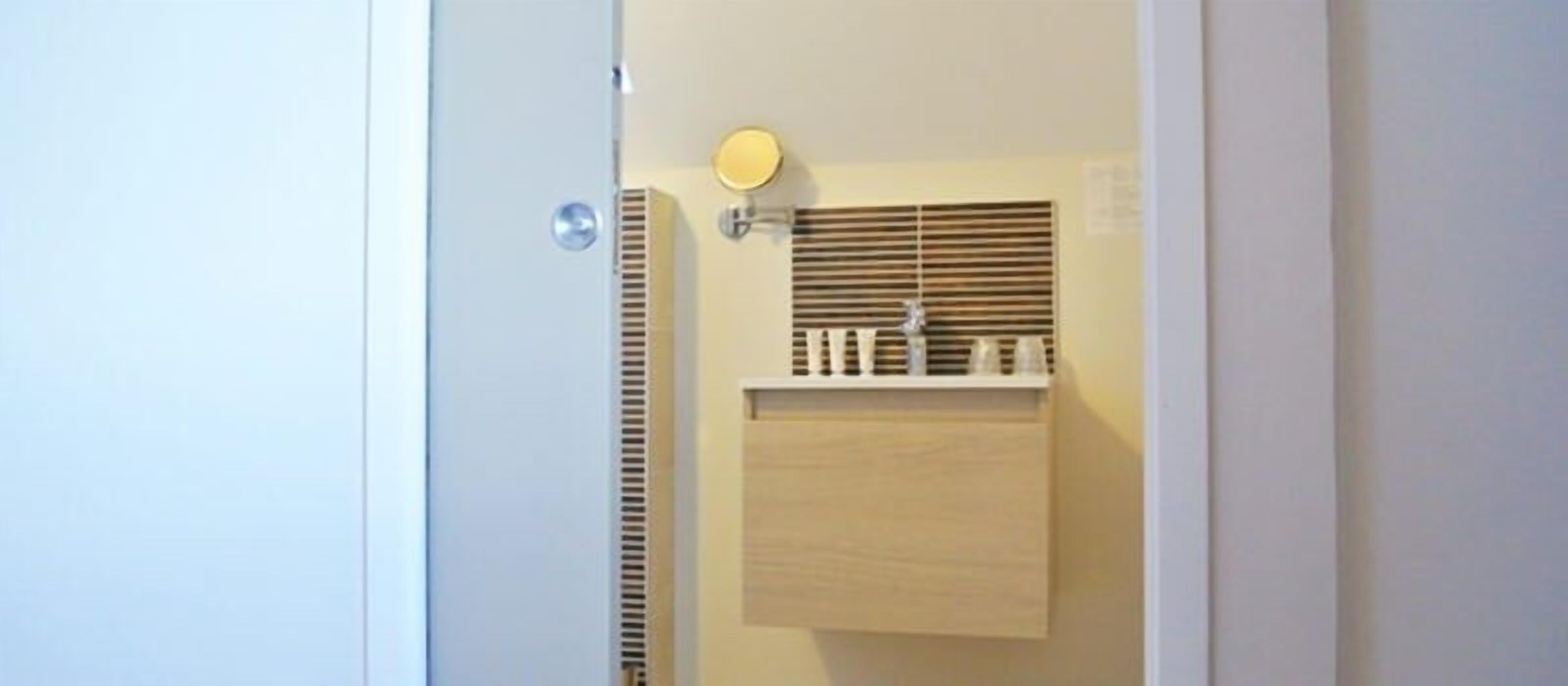 A bathroom with a mirror, a shelf with toiletries, and a vent.