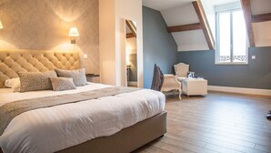 A bedroom with a large bed, a nightstand, a chair, and a window with a view. - Auberge du Moulin à Vent, The Originals Relais (Manou)