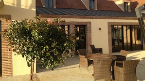 A patio area with wicker furniture, a brick wall, and a metal roof. - Auberge du Moulin à Vent, The Originals Relais (Manou)