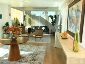 Una sala de estar moderna con un sofá, sillas, una mesa de centro y objetos decorativos.