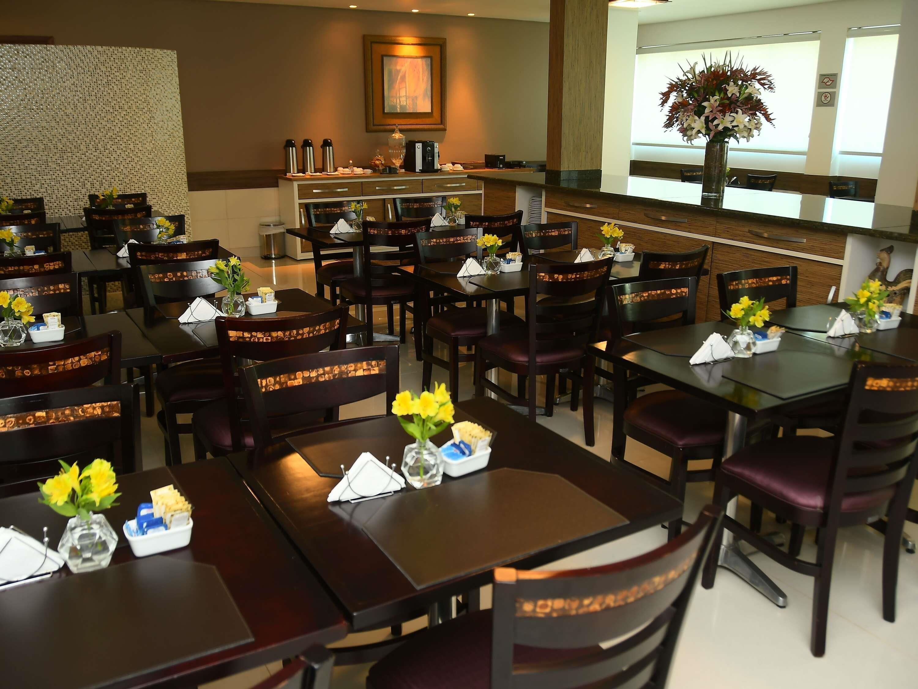 A hotel dining area with multiple tables, chairs, and a buffet station.