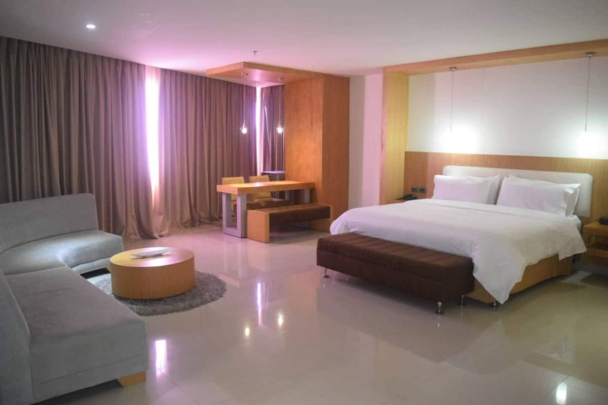 Ein modernes Hotelzimmer mit einem Bett, einer Couch, einem kleinen Tisch und einem Spiegel.