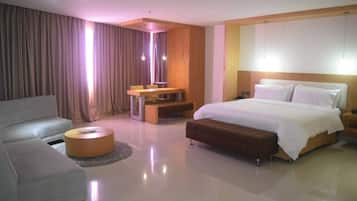 Une chambre d’hôtel moderne avec un lit, un canapé, une petite table et un miroir.