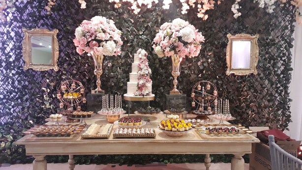 A table with various desserts and a tiered cake, set against a backdrop of floral decorations and framed mirrors. - Radisson Hotel Diamond Barranquilla (Barranquilla)