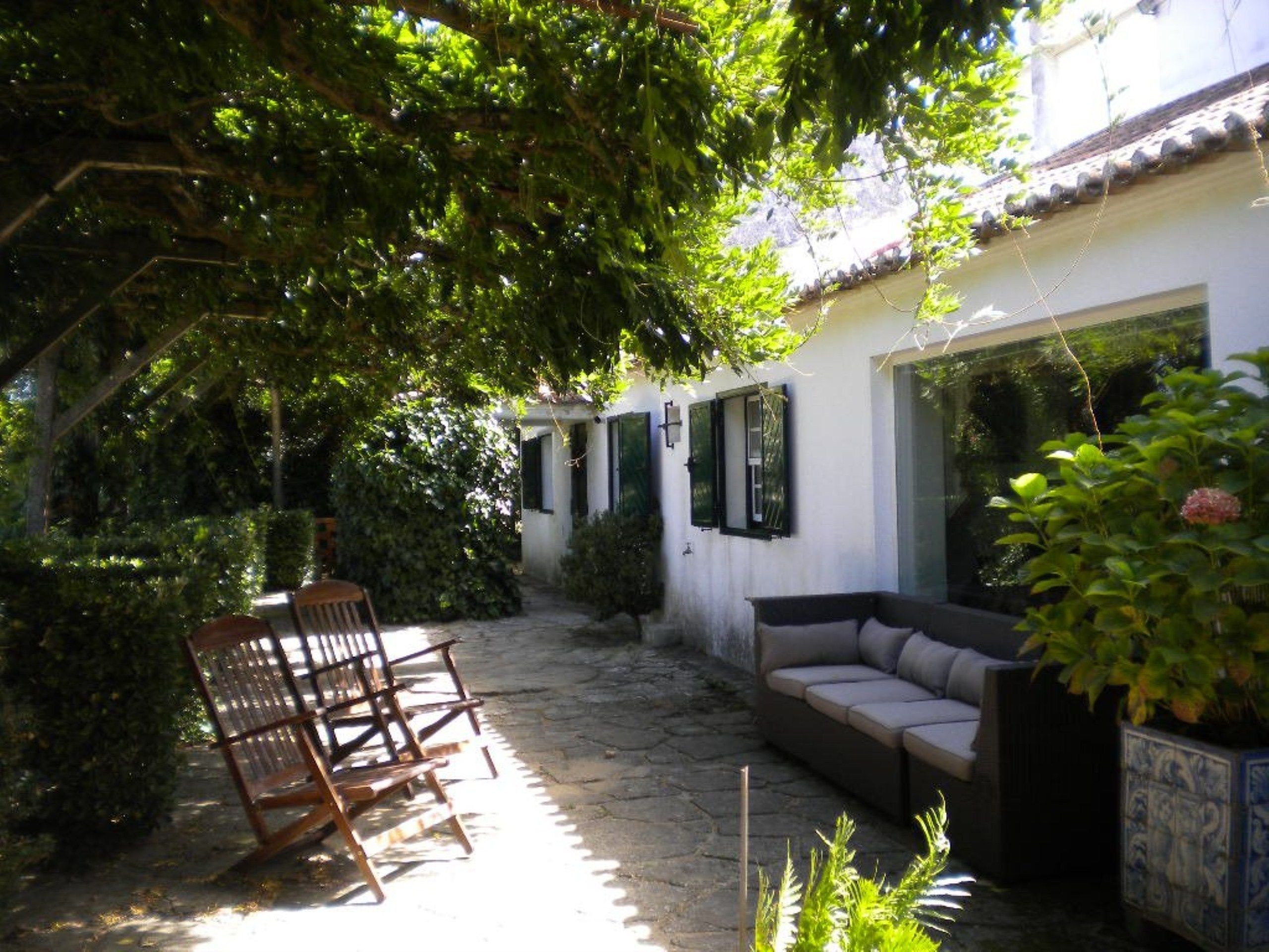 A courtyard with a stone floor, a wooden bench, a sofa, and a potted plant.