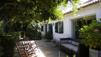 A courtyard with a stone floor, a wooden bench, a sofa, and a potted plant.