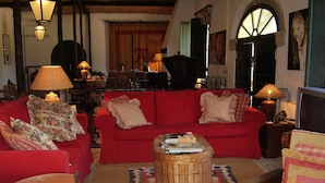 A cozy living room with a red sofa set, a wicker coffee table, and a patterned rug. - Quinta do Casalinho (Almeirim)