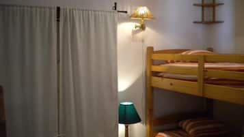 Habitación con literas, una cortina, estante en la pared y lámpara de noche.
