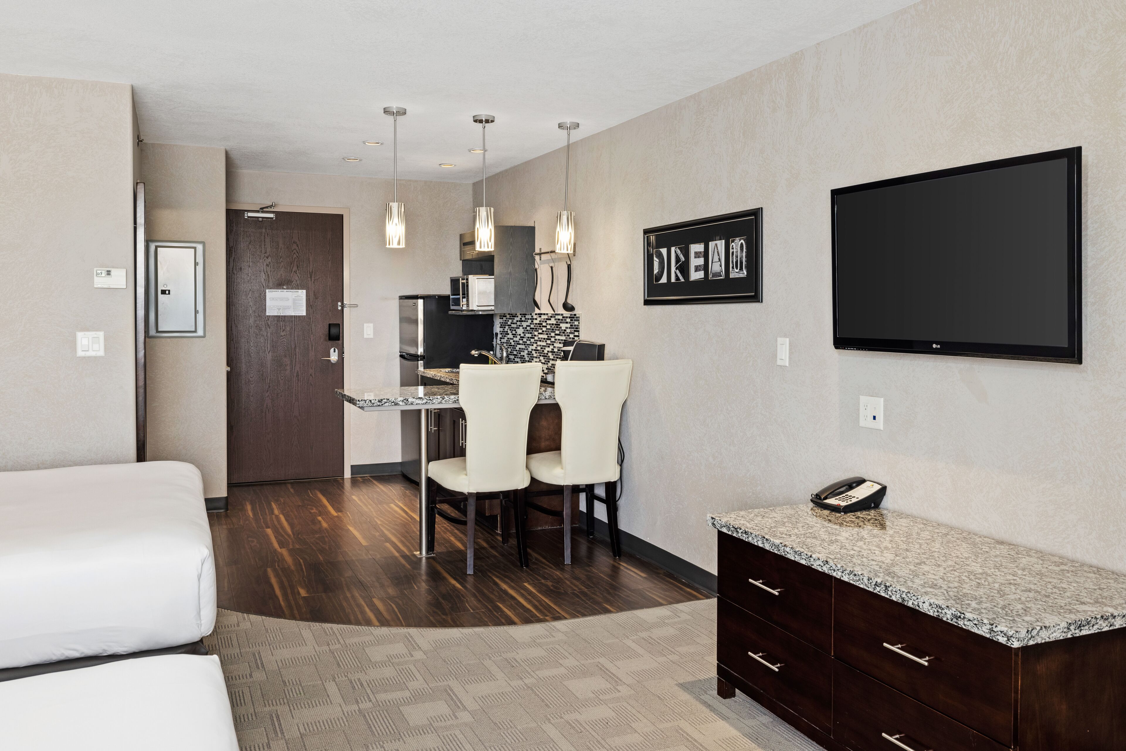 A hotel room with a bed, a desk, a chair, a TV, and a phone on a counter.