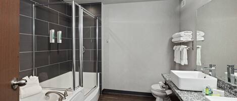 Un baño moderno con ducha envuelta en vidrio, una bañera independiente, un lavabo y un inodoro.