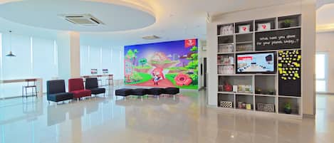 A modern lobby with a large mural, seating area, and a display wall with various items.