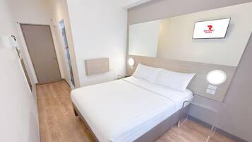 A modern hotel room with a bed, a TV mounted on the wall, and a wooden floor.