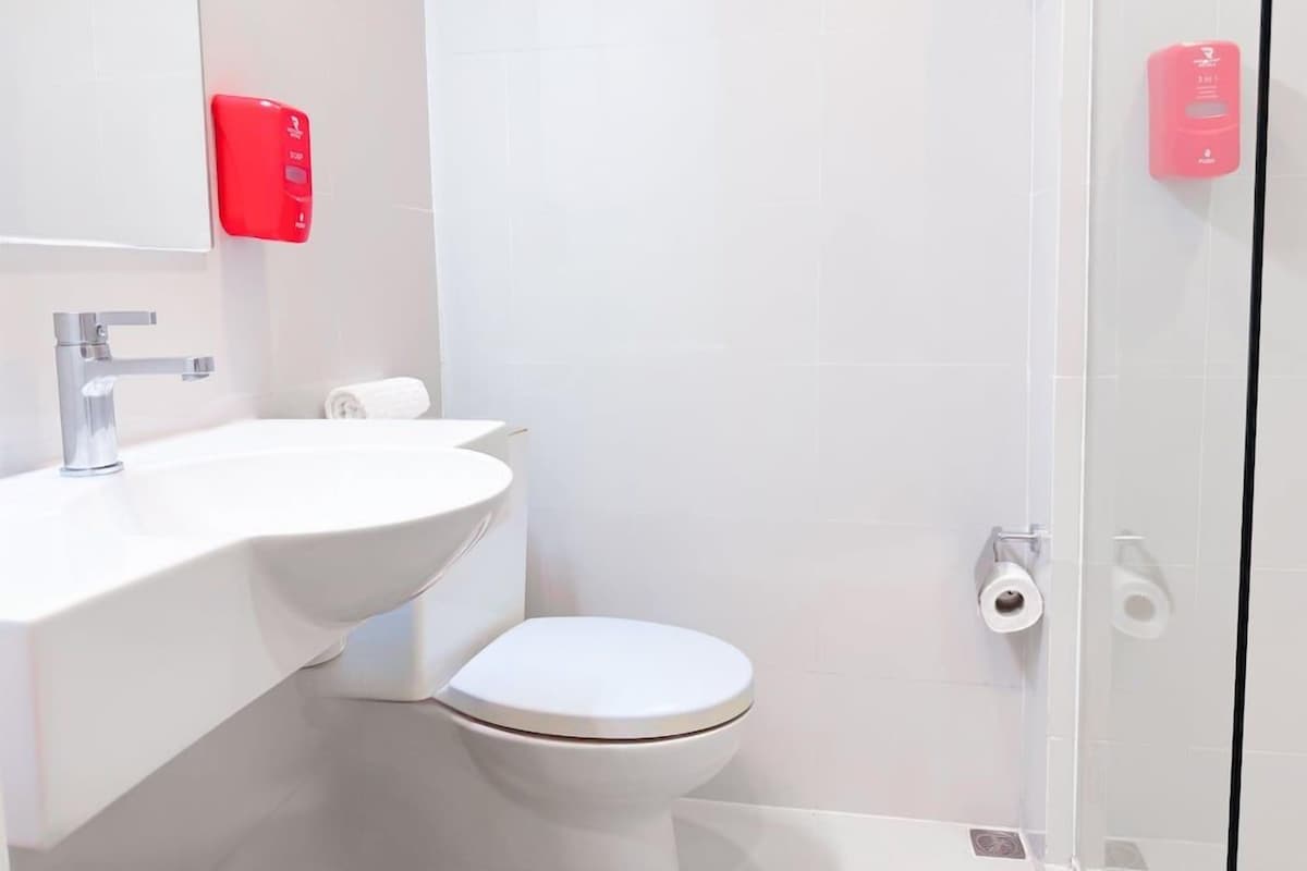 Un baño moderno con lavamanos, inodoro y ducha blancos.