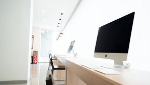 Ein moderner Arbeitsraum mit einem großen Apple iMac auf einem Schreibtisch, einer Glastrennwand und einem minimalistischen Design.