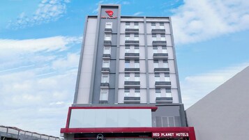 Un edificio de Red Planet Hotels con un diseño moderno, varios pisos y un logotipo destacado en la parte superior.
