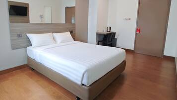 Une chambre d’hôtel avec un lit, un bureau, une chaise, une télévision et une porte.