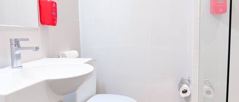 A modern bathroom with a white sink, a toilet, and a glass shower enclosure.