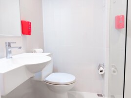 Un baño moderno con un lavamanos blanco, un inodoro y una cabina de ducha de vidrio.