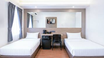 Habitación de hotel con dos camas, un escritorio, una silla, una cafetera y un refrigerador pequeño.