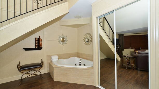 Amplia sala de estar con una bañera grande, un banco y una escalera que conduce a un nivel superior.