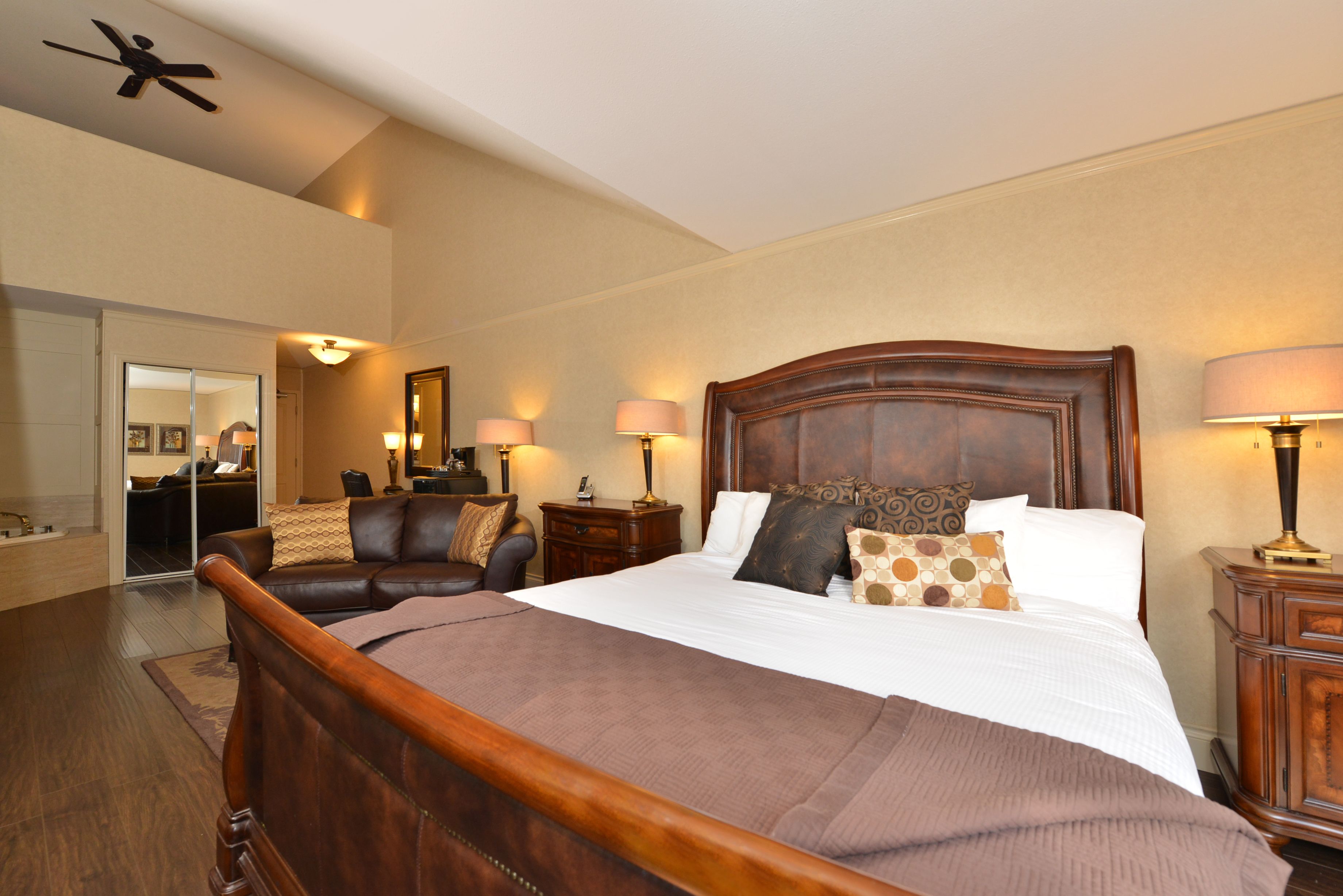 A spacious bedroom with a large bed, wooden headboard, and two bedside tables with lamps.