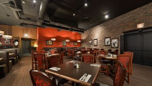 Un restaurante con mesas y cabinas, paredes de ladrillo y cuadros en la pared.