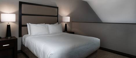 A hotel room with a large bed, two bedside tables with lamps, a ceiling fan, and a modern design.