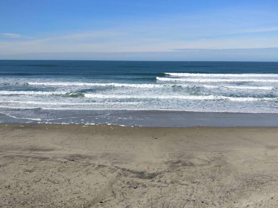 Una playa con olas acercándose a la orilla bajo un cielo despejado.