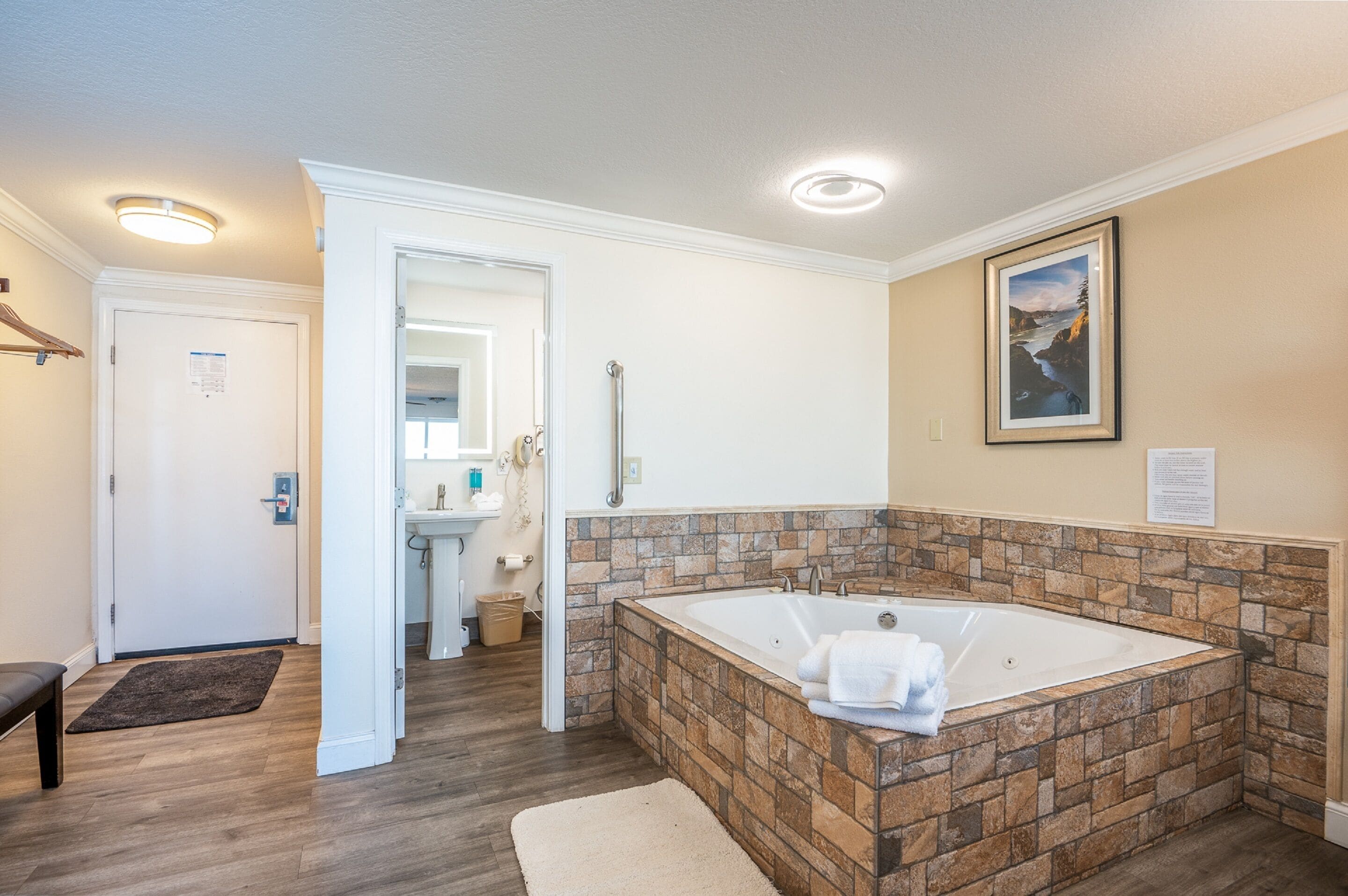 Ein Badezimmer mit einer Wand aus Stein, einer großen Badewanne und einem gerahmten Bild.