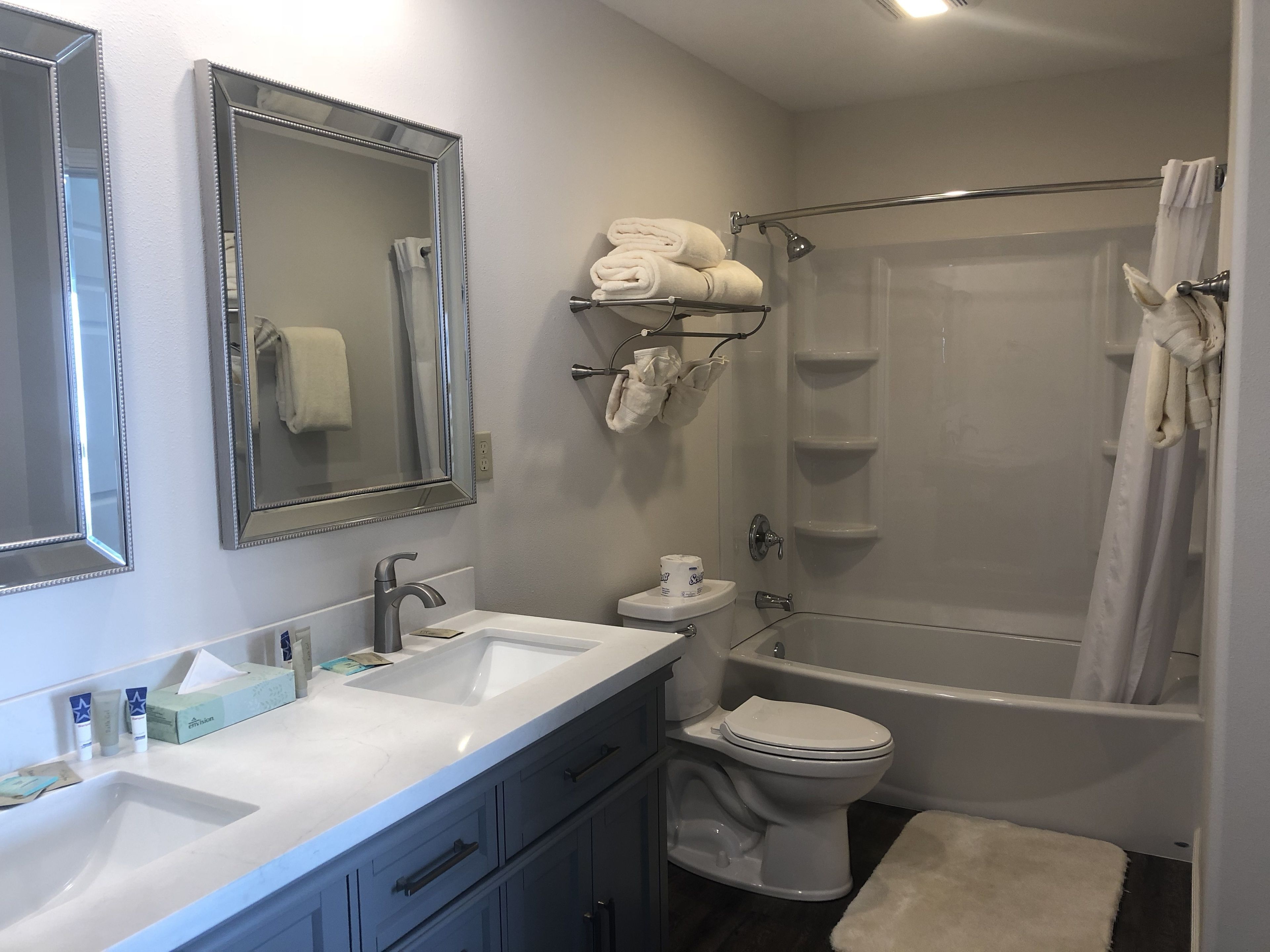 A bathroom with a sink, toilet, and shower. There are towels and toiletries on the counter.