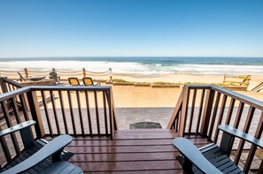 A wooden deck with chairs overlooking a beach. - Sailor Jack's Oceanfront Inn (Lincoln City)