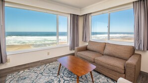 A room with a large window offering a view of the beach and ocean.