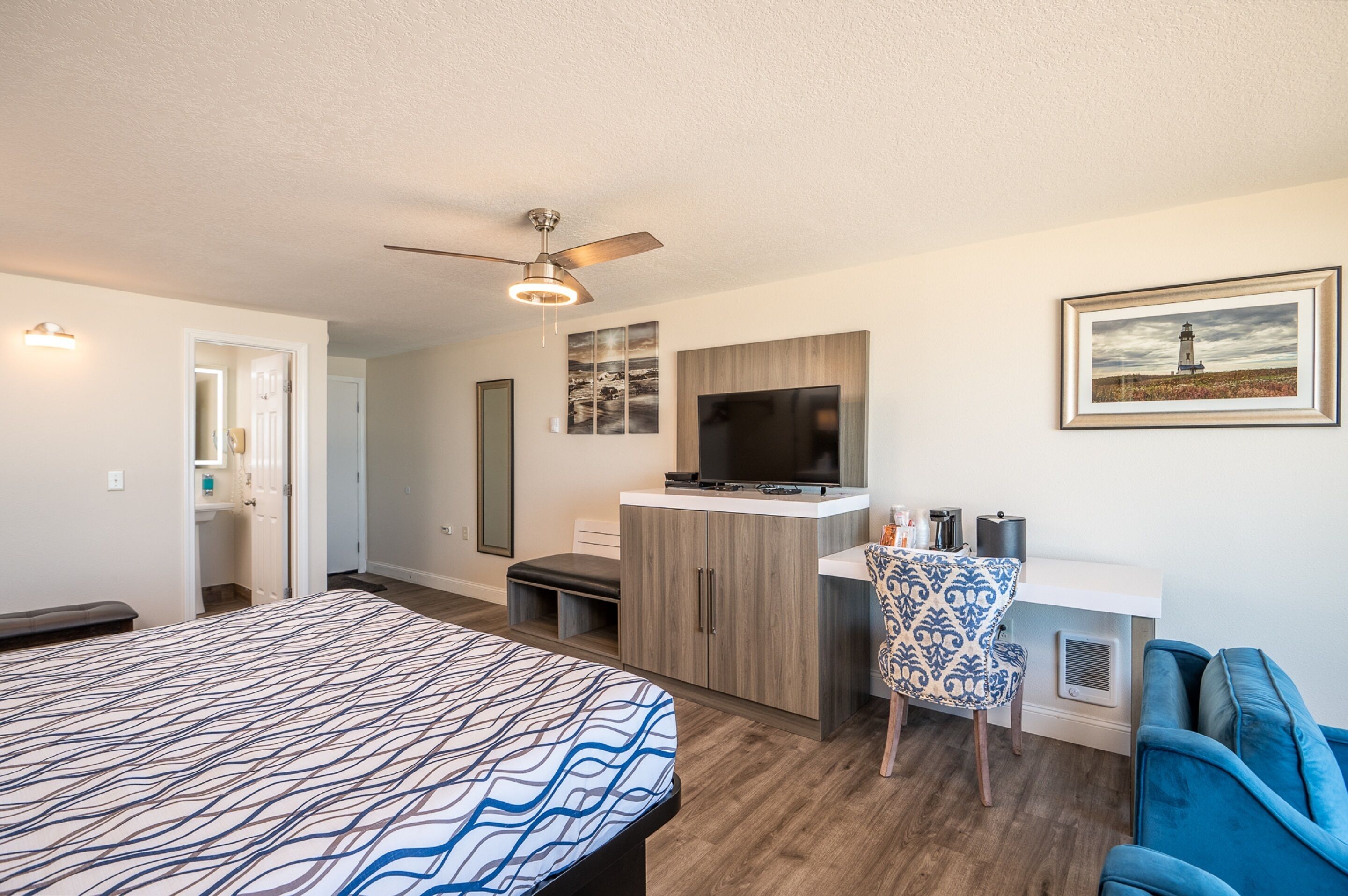A modern room with a bed, a desk, a chair, a television, and a ceiling fan.