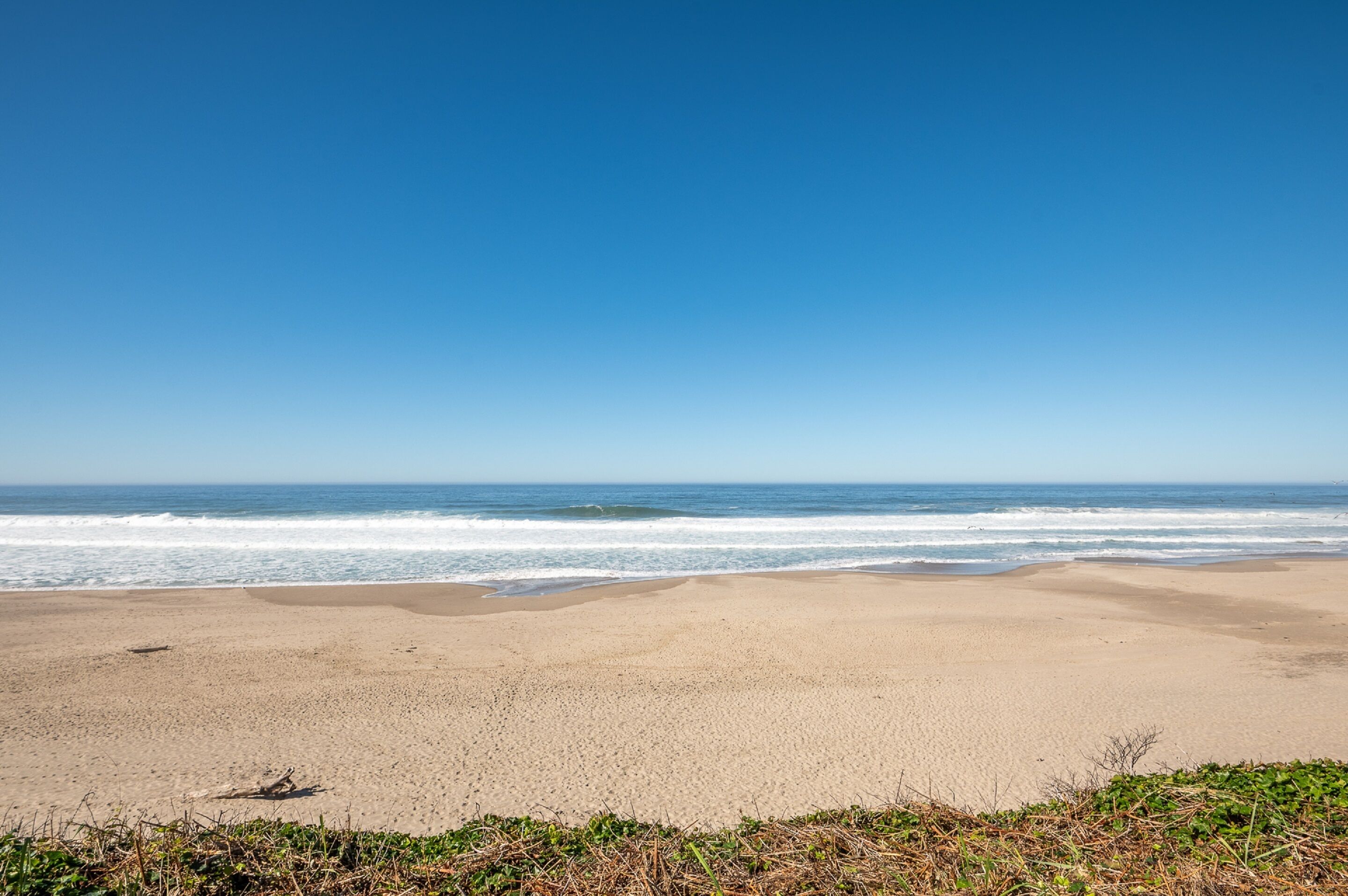 A beach with a clear sky and calm sea.