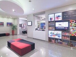 Un vestíbulo moderno con mostrador de recepción, zona de estar y una pared con pantallas digitales y un tablón de anuncios.