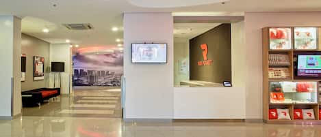 Um hall de hotel moderno com uma mesa de recepção, um mural com vista para a cidade e uma exposição com tema Red Planet.