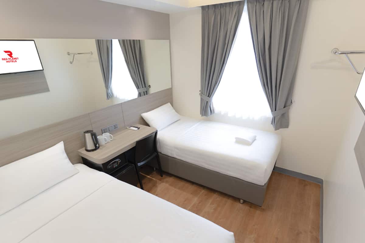 Quarto de hotel com duas camas, uma escrivaninha, um espelho e uma televisão.