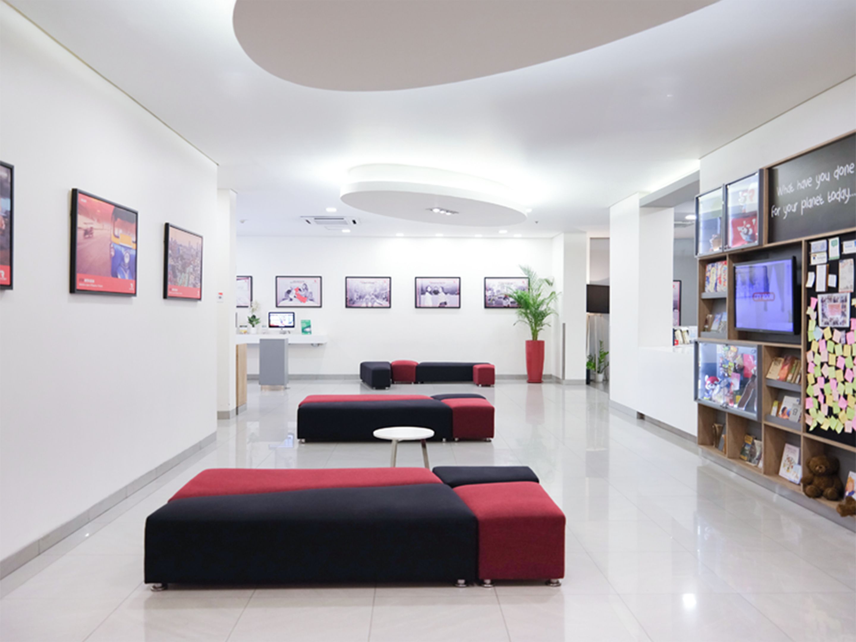 A modern lobby with a reception desk, seating area, and a wall with framed pictures.