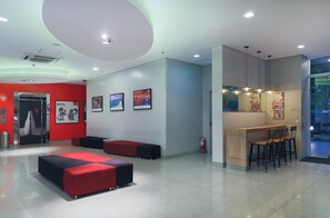 A modern lobby with a reception desk, seating area, and artwork on the walls. - Red Planet Ortigas (Pasig)