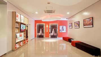Un hall d'entrée moderne avec un mur d'accent rouge, un comptoir de réception et un espace salon.