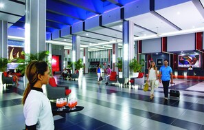 A spacious lobby with a checkered floor, seating areas, and a large screen displaying a video.