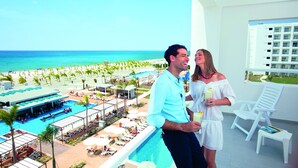 A balcony with a view of a pool area, lounge chairs, and a building in the background.