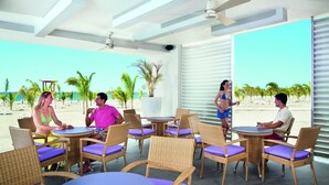 A beachside lounge with wicker furniture and large windows overlooking the ocean. - Hotel Riu Playa Blanca - All Inclusive (Rio Hato)