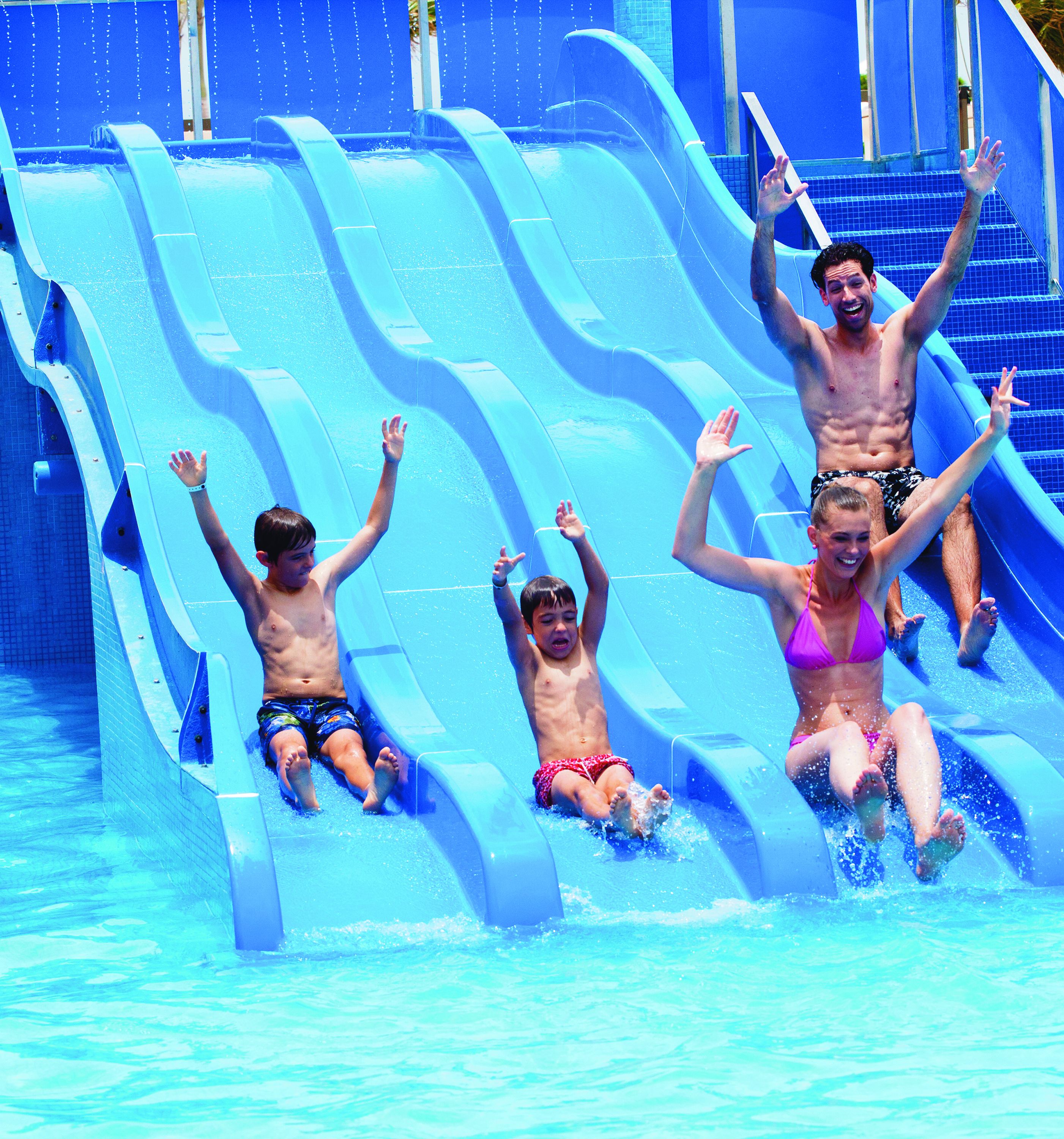 A water slide with multiple lanes, a pool, and a staircase leading to a higher platform.