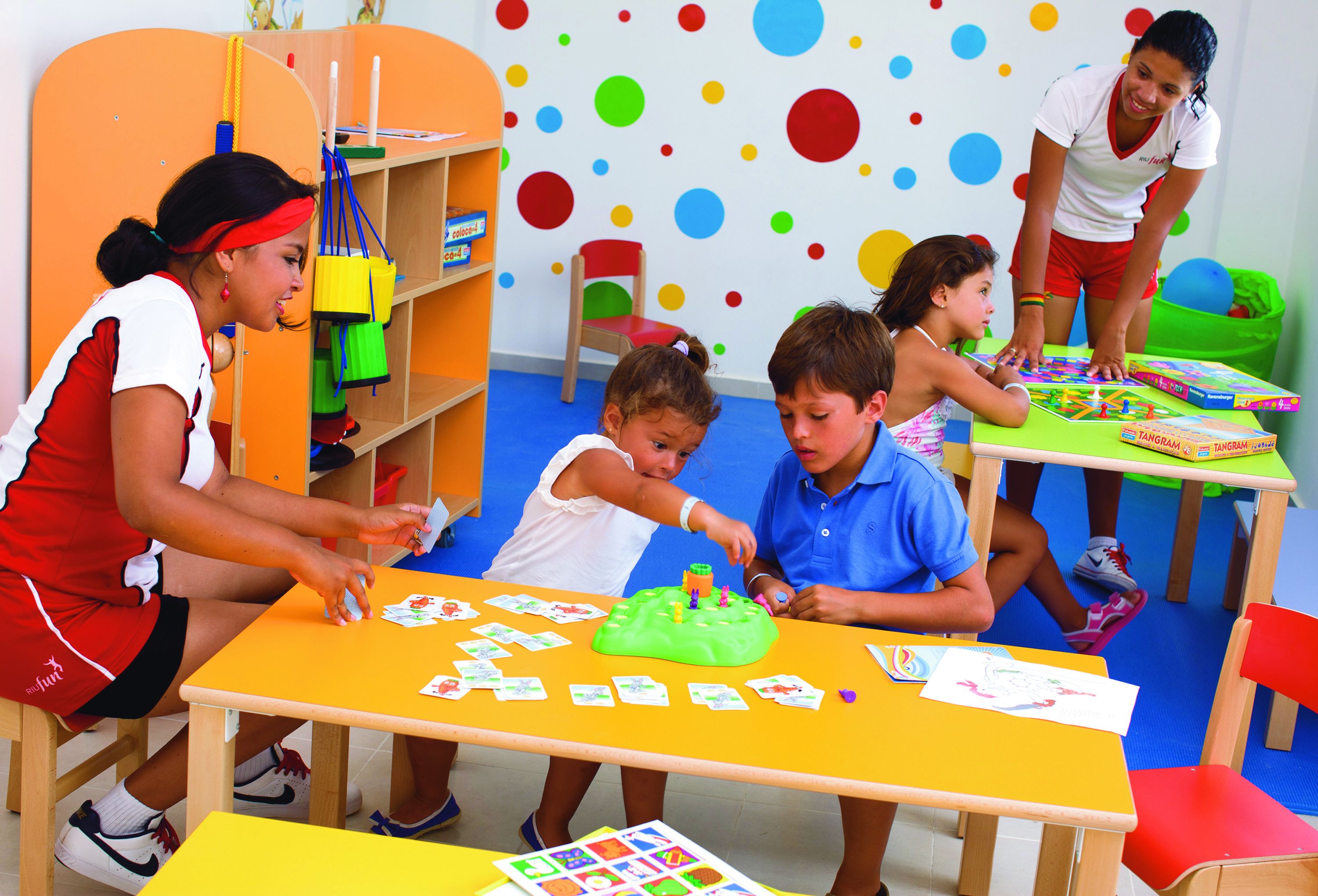 A classroom with children engaged in various activities, colorful educational materials, and a teacher assisting them.