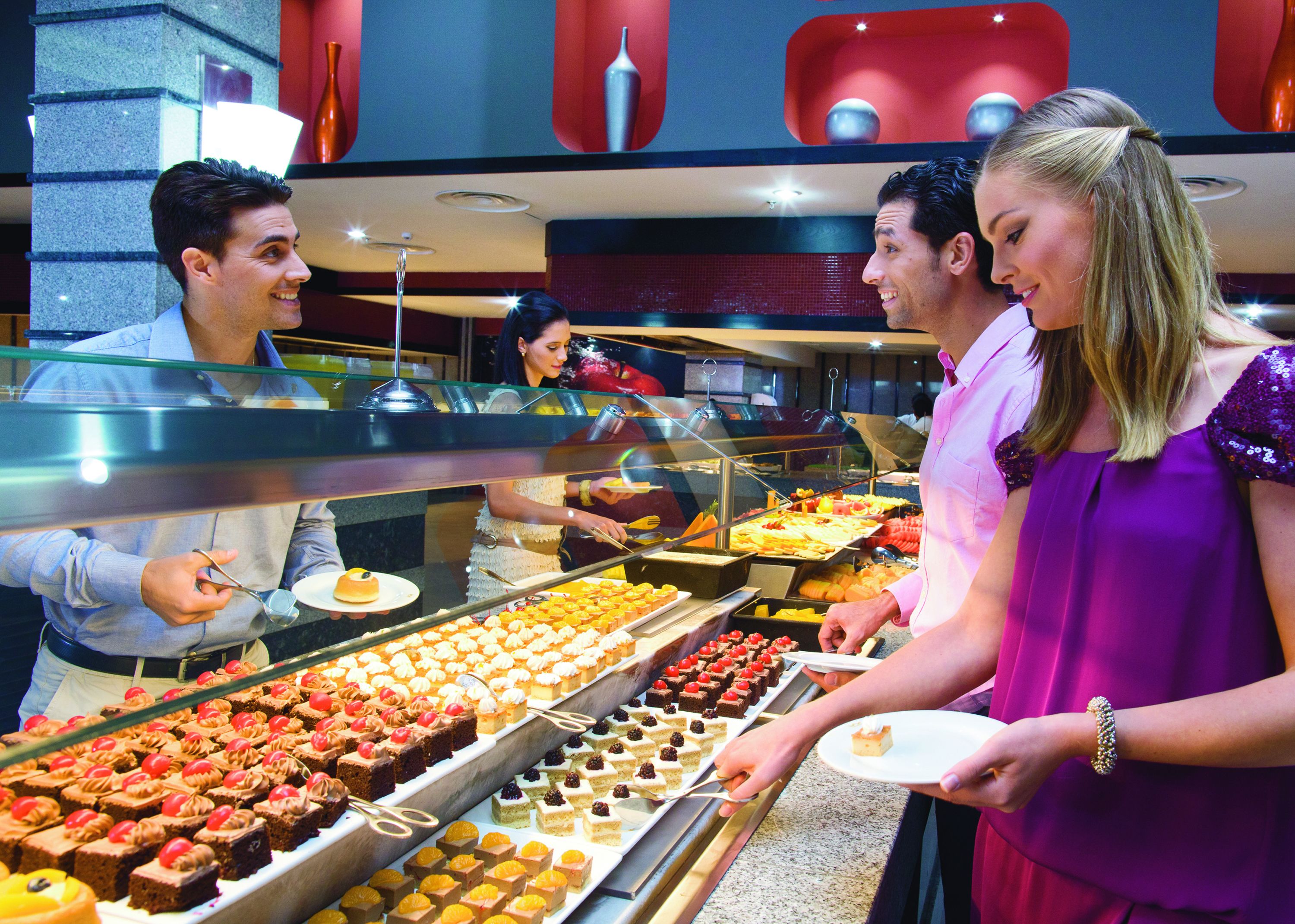 Buffet com diversos doces e uma pessoa servindo comida.