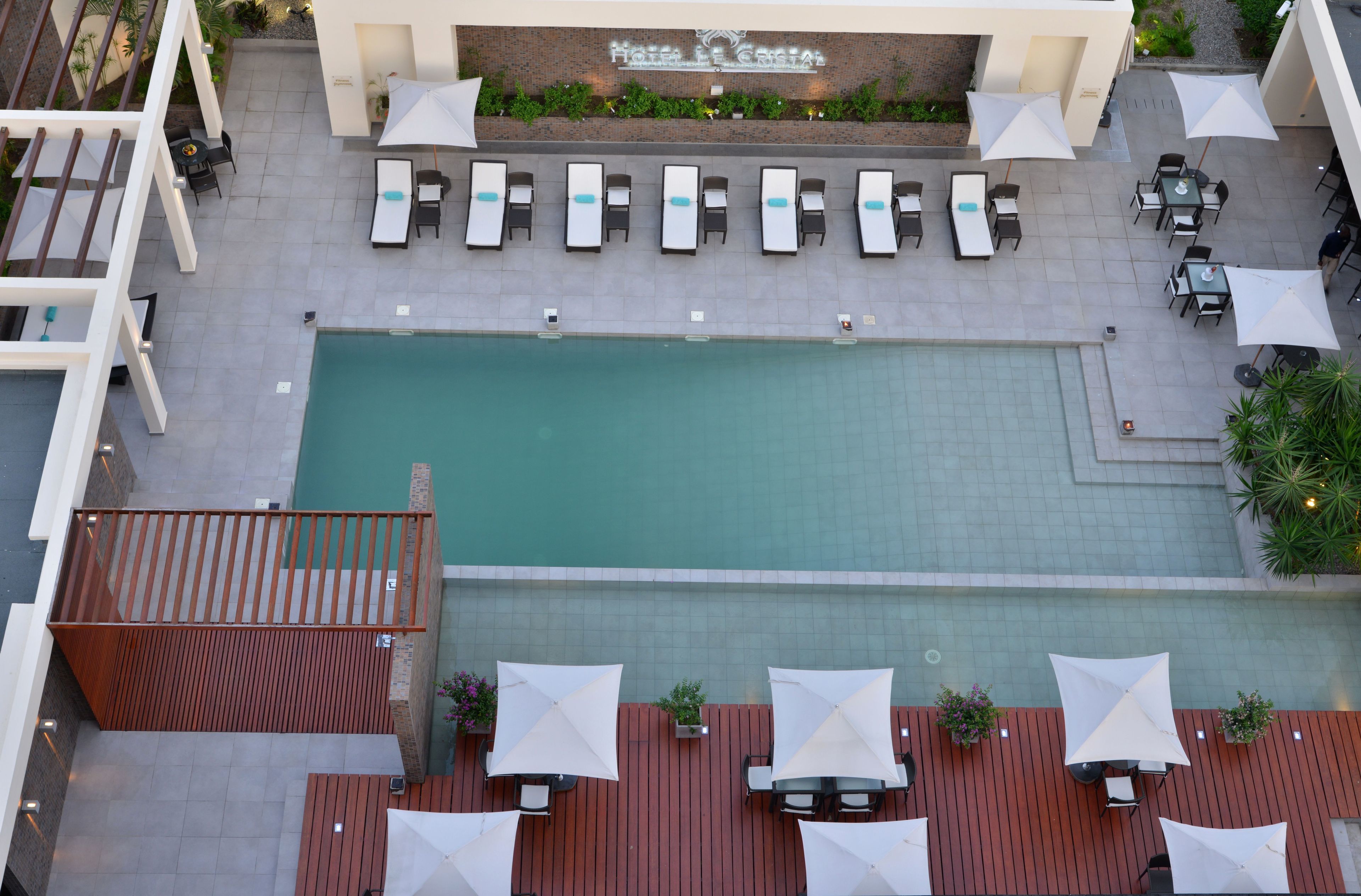 Zona de piscina al terrat amb gandules i ombrelles, un pont de fusta i un cartell que diu 'Hotel de Costa'.