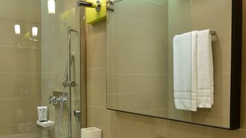 A modern bathroom with a glass-enclosed shower, a white sink, and a mirror above it.