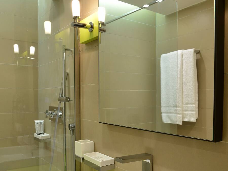 A modern bathroom with a glass-enclosed shower, a white sink, and a mirror above it.