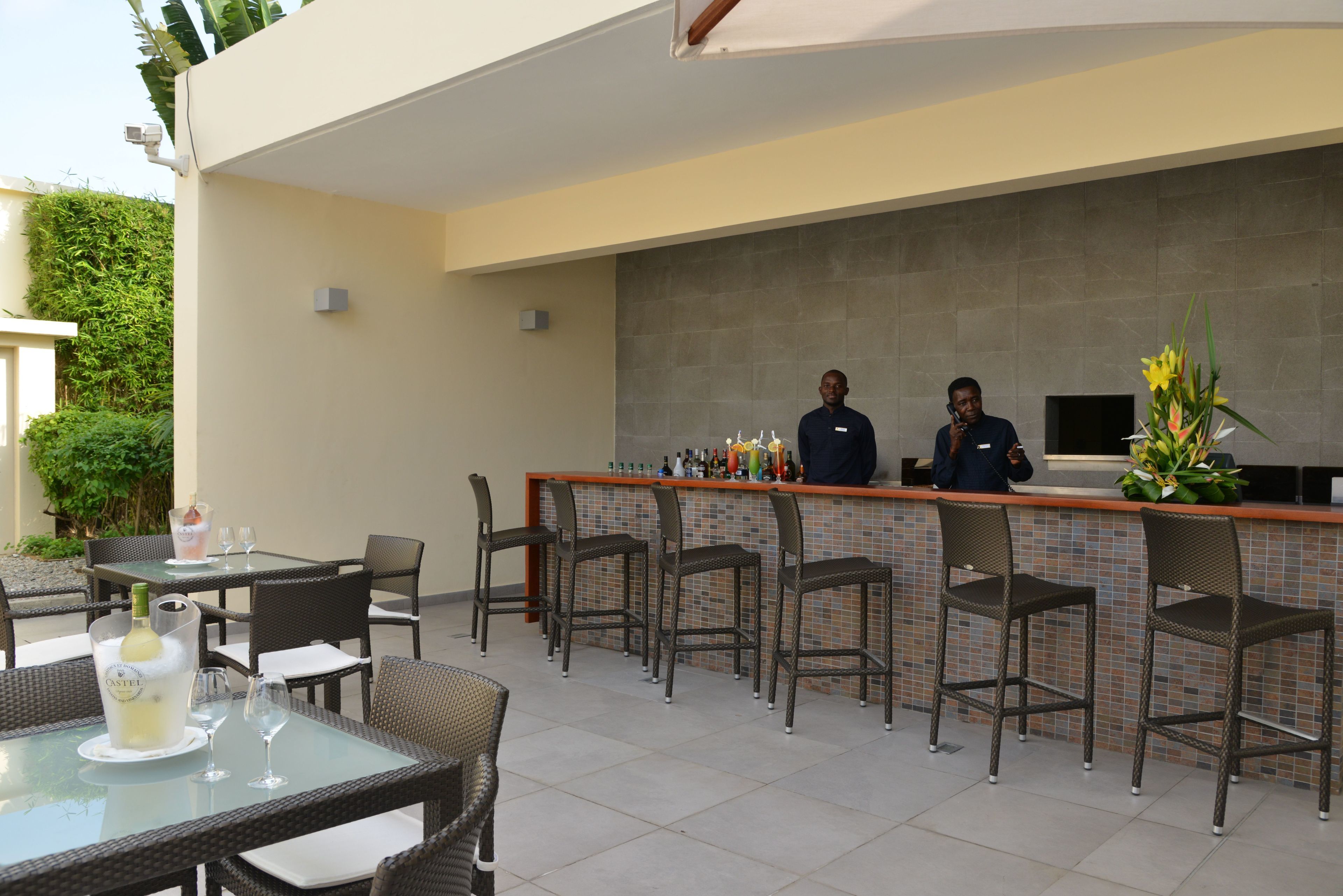 An outdoor bar area with wicker chairs and a tiled backsplash.
